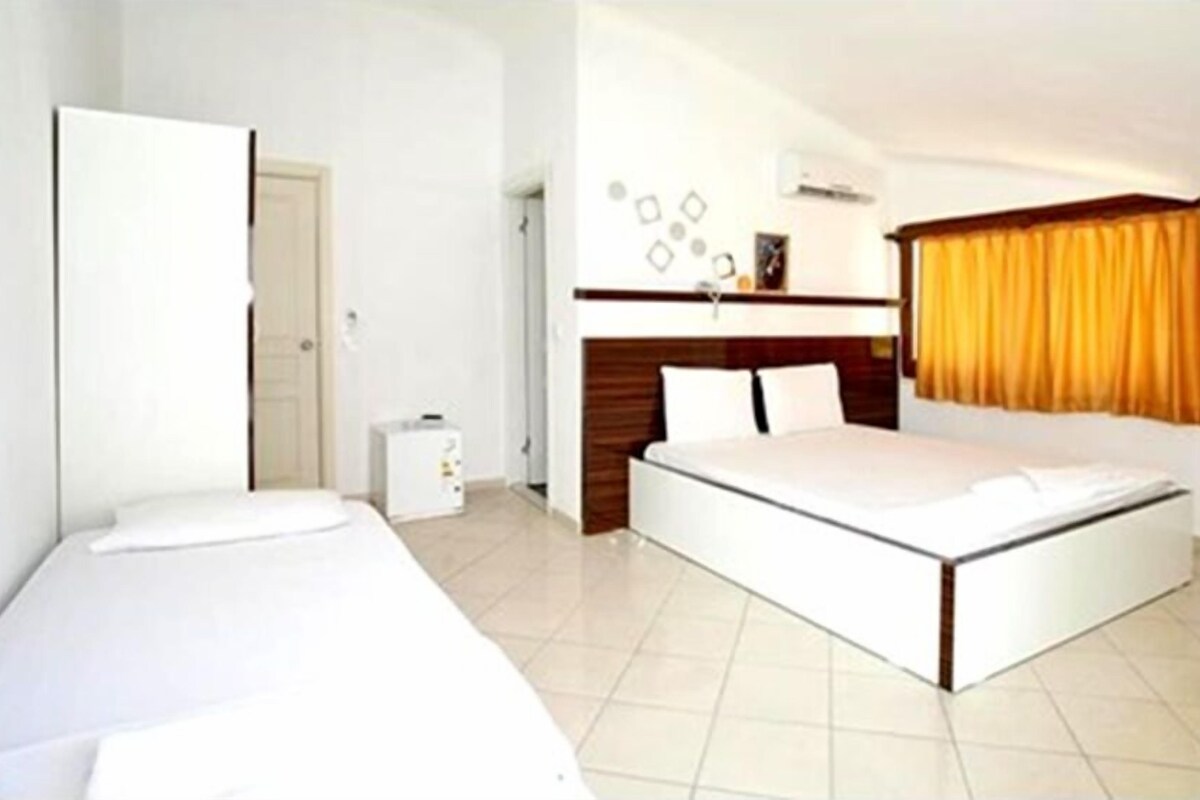 A bedroom with a bed, a bedside table, a wardrobe, and a small cabinet.