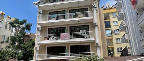 A multi-story building with balconies, a sign reading 'Hakan Pansiyon,' and a storefront with a sign that reads 'Hakan Pansiyon.'