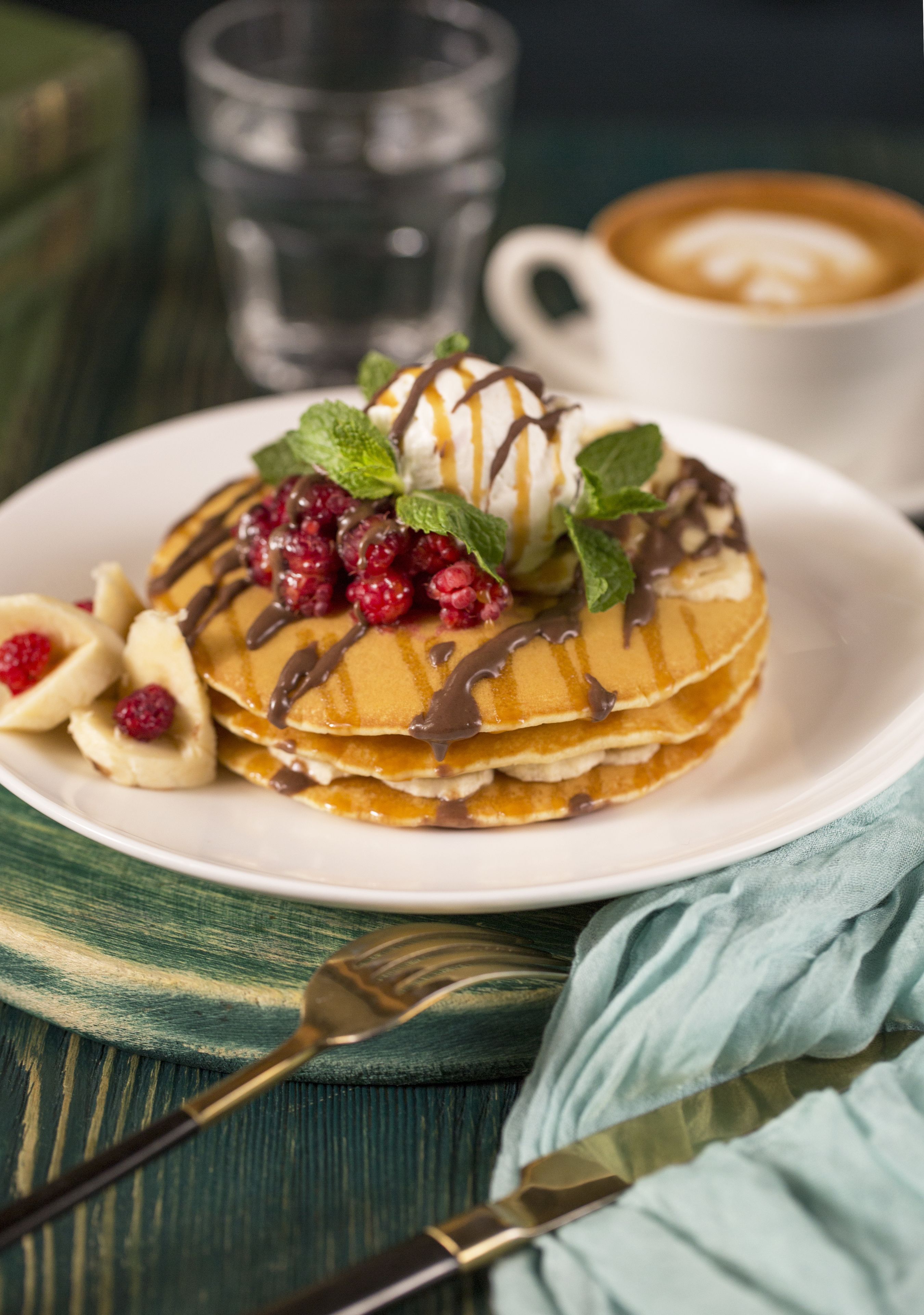 Ein Teller Pfannkuchen mit Sirup, Beeren und Minzblättern.
