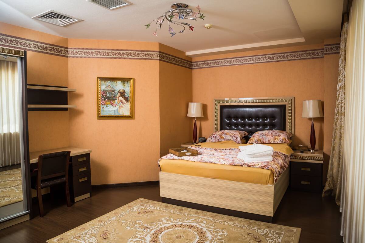 A bedroom with a bed, bedside tables, a desk, and a chair.