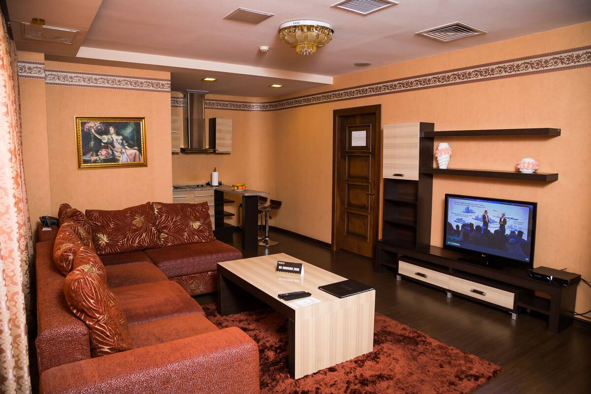 A living room with a sectional sofa, a coffee table, a television, and a fireplace.