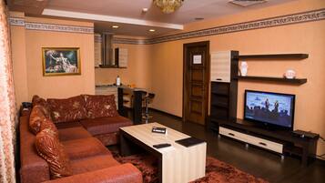 A living room with a sectional sofa, a coffee table, a television, and a fireplace.
