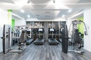 Ein Fitnessstudio mit Laufbändern, Kraftgeräten und einer Spiegelwand.