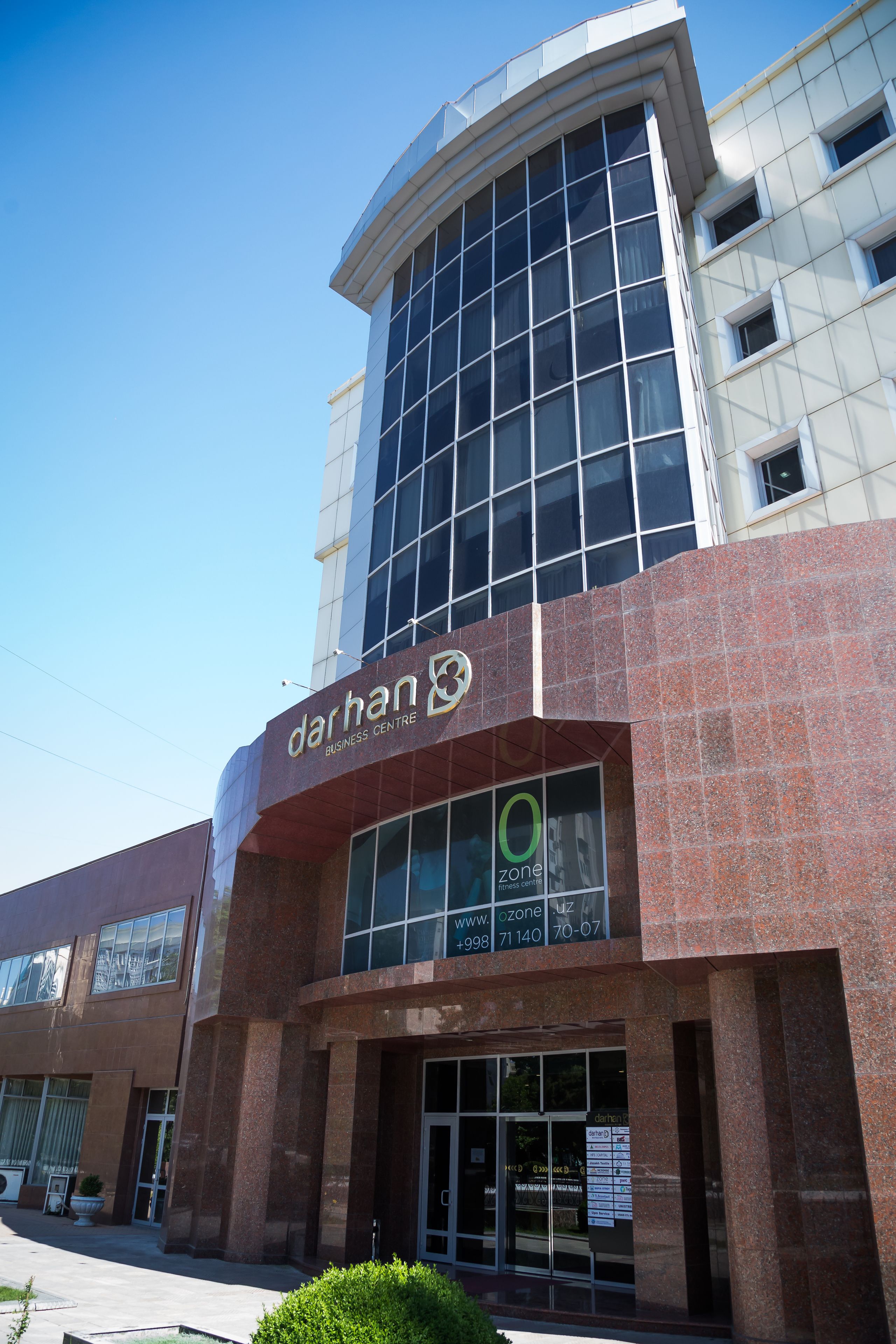 Un edificio moderno con una vasta facciata in vetro e un cartello con la scritta 'darhan business centre'.