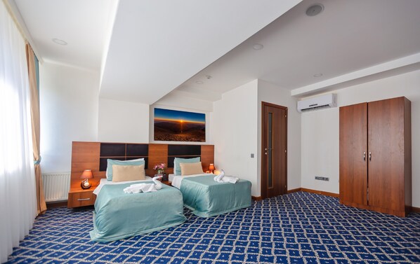A hotel room with two beds, a large window with curtains, a wall-mounted air conditioner, and a wooden wardrobe. - Hotel 28 (Baku)