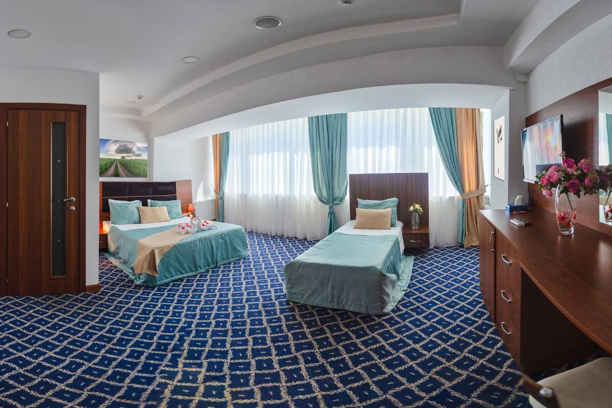 A hotel room with two beds, a large mirror, a wooden dresser, and a fruit bowl on the dresser.
