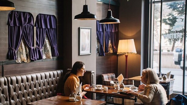 A cozy restaurant with leather booths, wooden tables, and hanging pendant lights. - Hotel 28 (Baku)
