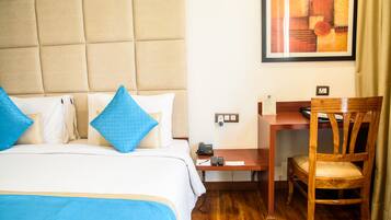 Una habitación de hotel con una cama, un escritorio, una silla y un cuadro en la pared.