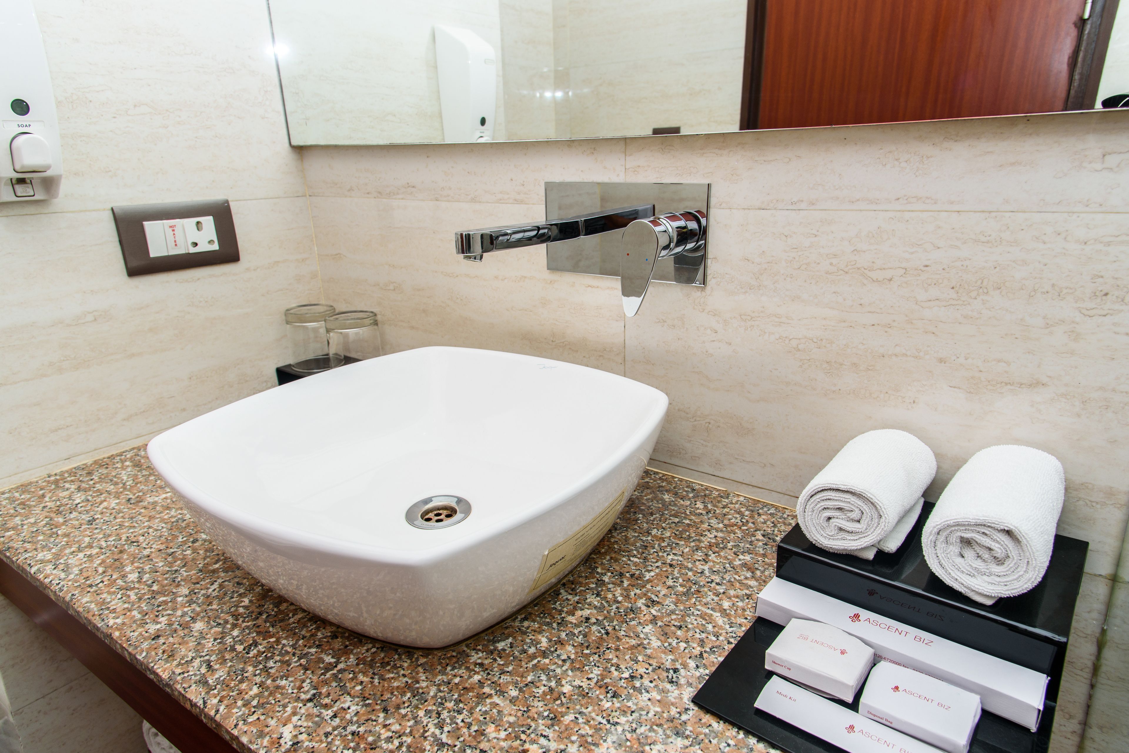 A bathroom with a large white sink, a mirror, and a towel rack with towels.