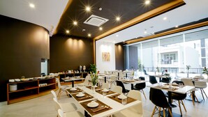Un comedor moderno con mesas dispuestas para comidas, un amplio ventanal con vistas a la ciudad e iluminación empotrada en el techo.