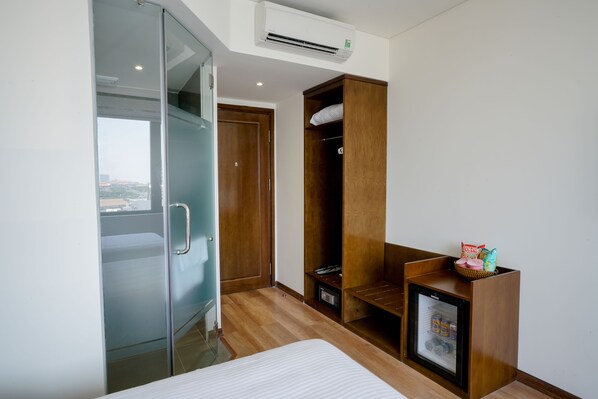 A hotel room with a bed, a wardrobe, a small refrigerator, and a window with a view. - Onami Hotel (Da Nang)