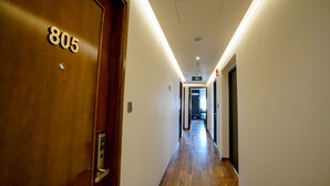 Un pasillo con una puerta de madera identificada con el número 805 y un moderno aplique a lo largo del techo.