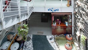 Ein mehrgeschossiges Interieur mit einer Treppe, einem Empfangsbereich und einer Sitzecke mit Kissen und einer kleinen Wasserspiels.