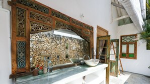 Ein Badezimmer mit Steinwand, einem Holzdekorbogen und einem weißen Waschbecken.