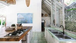 Eine Küche mit Holzarbeitsplatte, Gasherd, Spüle und einer Steinwand.