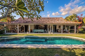Une maison avec une piscine, un patio couvert et un jardin.