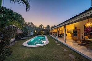 A swimming pool with a surrounding garden and a covered outdoor seating area. - Villa Papaya (Pecatu)