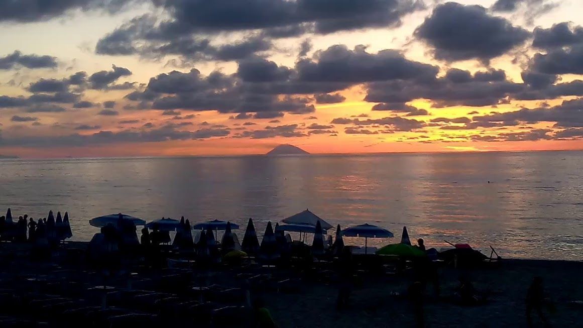 Une plage avec des parasols et des gens.