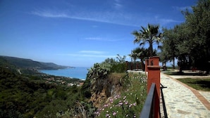 A coastal view with a pathway leading to a building, surrounded by greenery and a clear sky. - Residenza Mediterranea (Zambrone)