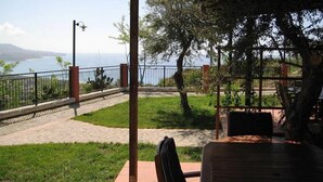 A covered outdoor seating area with a view of the sea and mountains. - Residenza Mediterranea (Zambrone)