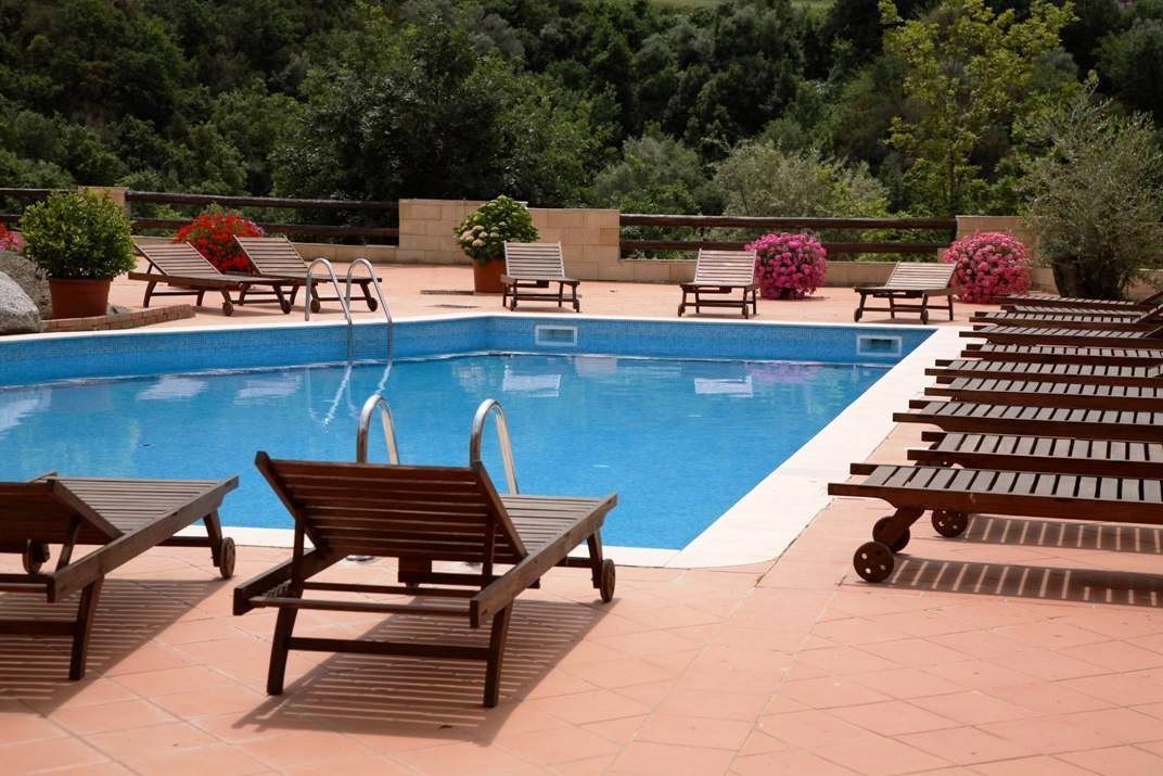 Ein rechteckiger Pool mit Holzliegen und Pflanzen in Töpfen darum.