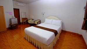 A hotel room with a bed, a desk, a chair, a small table, and a wardrobe.