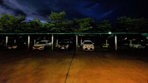 A parking area with three cars parked under a covered structure.