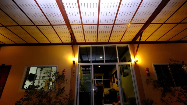 A building entrance with a glass door, potted plants, and a wooden ceiling structure.