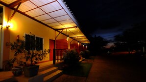 A building with a covered porch, steps leading up to the entrance, and potted plants.