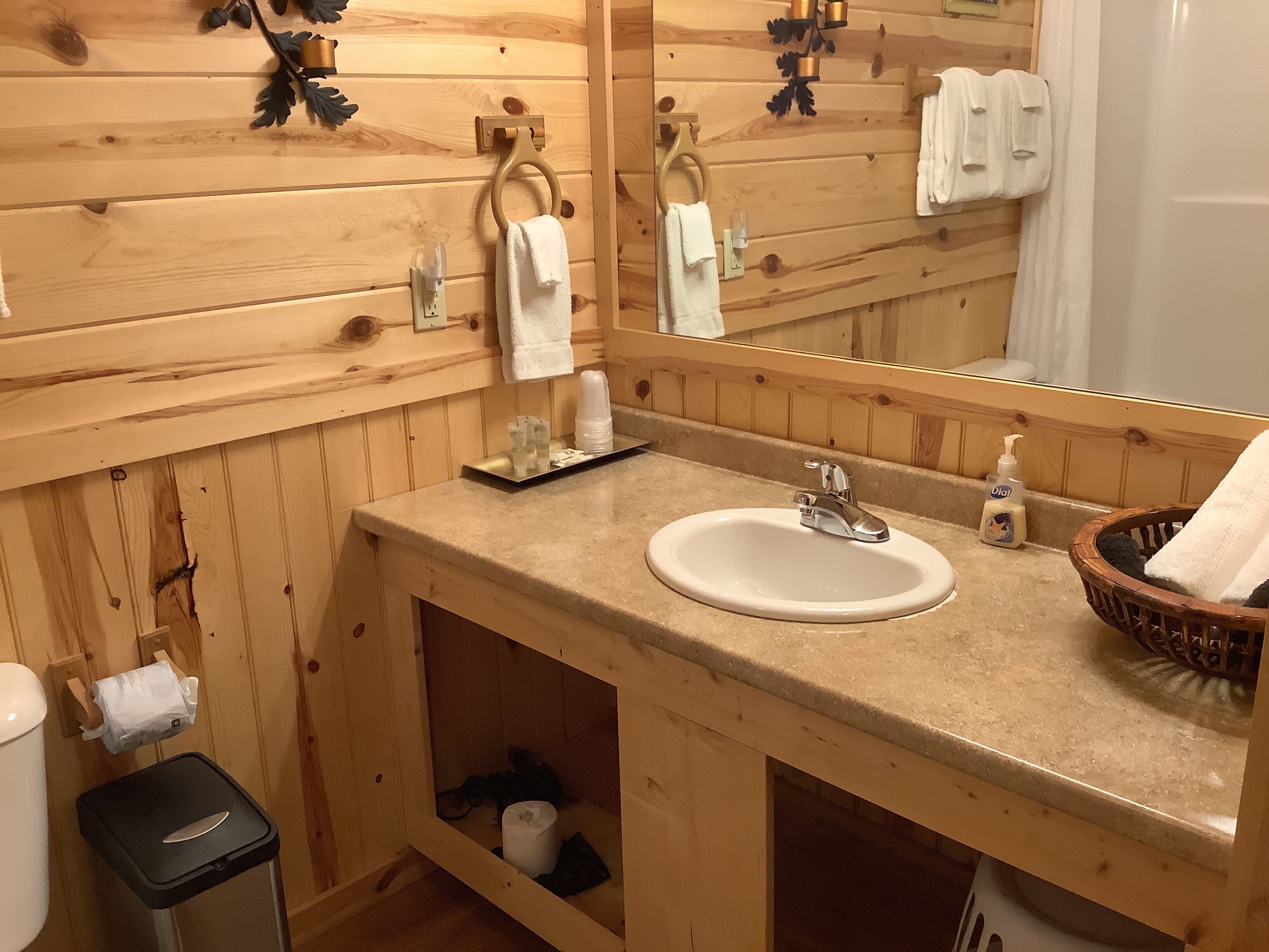 Un baño de madera con lavamanos, espejo y barra para toallas.