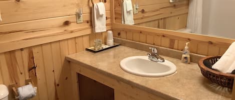 Un baño de madera con lavamanos, espejo y barra para toallas.