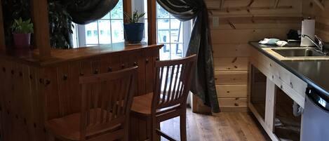 Un intérieur rustique en bois, avec un coin bar, des chaises en bois, un évier et des plantes en pot.