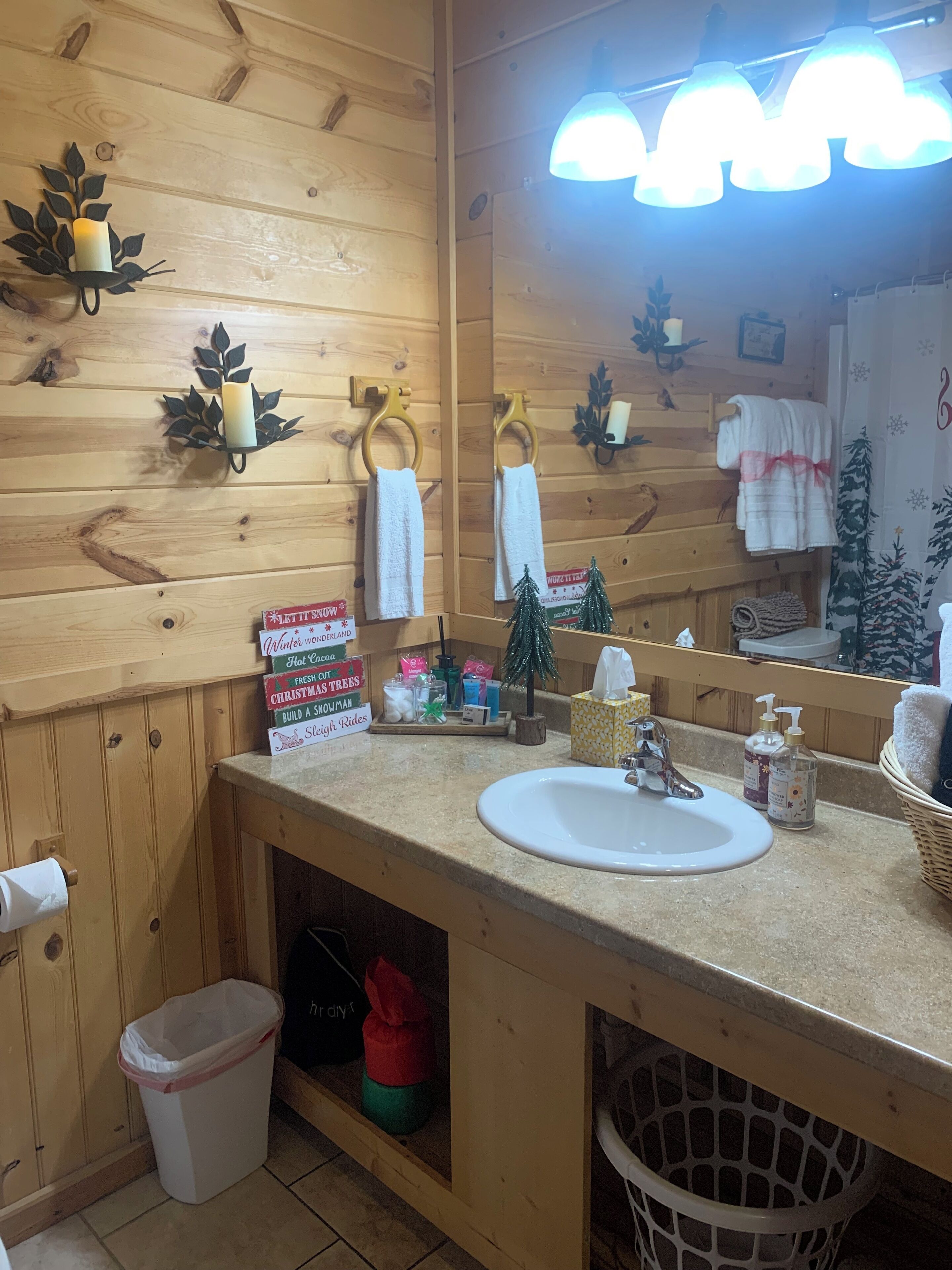 A bathroom with wooden paneling, a sink, a mirror, and a towel rack.