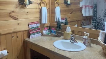 A bathroom with wooden paneling, a sink, a mirror, and a towel rack.