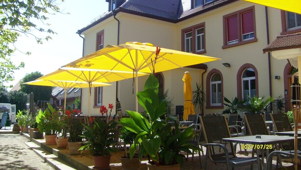 Een gebouw met gele parasols en potplanten ervoor.
