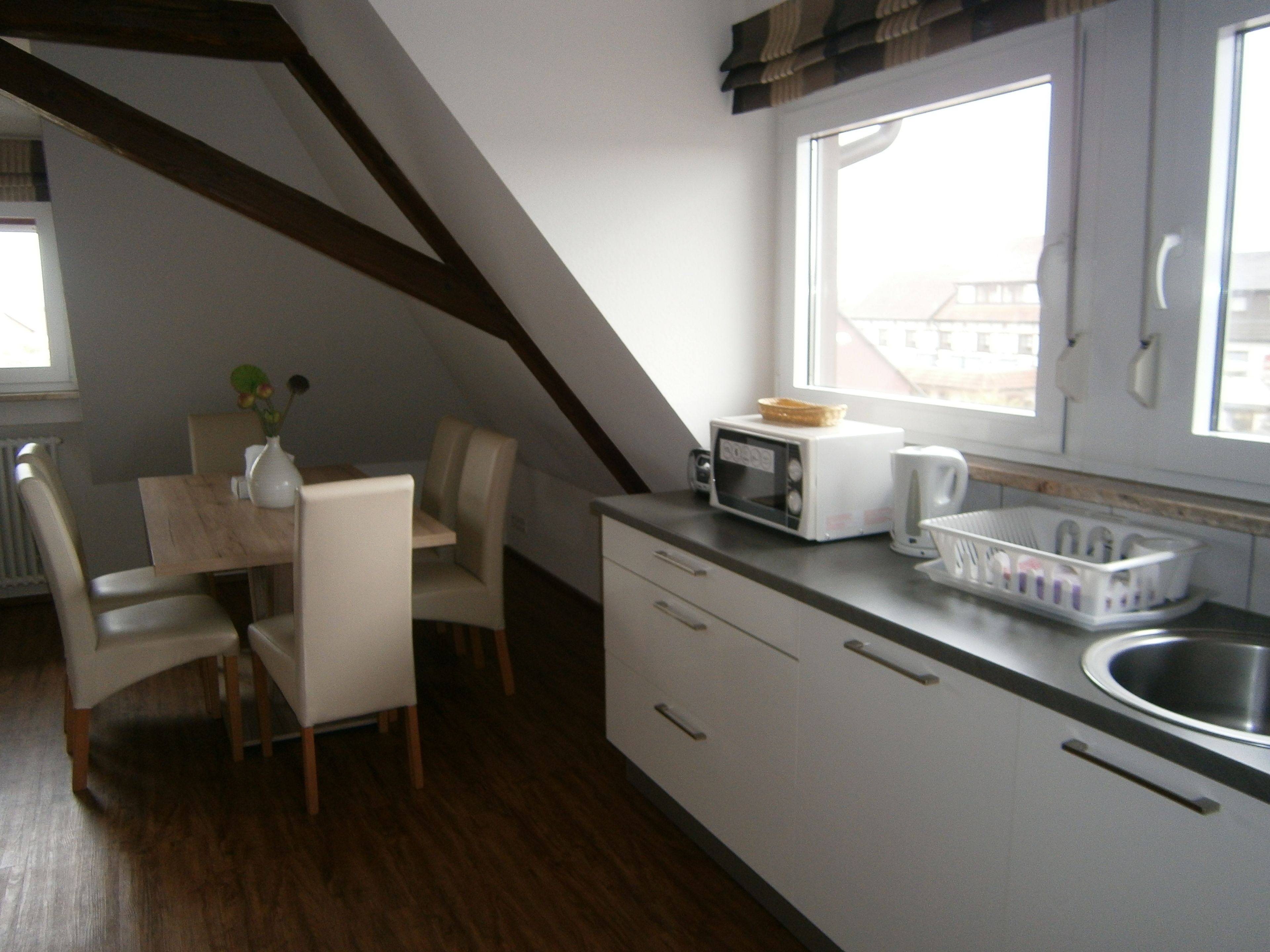 A compact kitchen with a dining area, featuring a microwave, toaster, and a small sink.