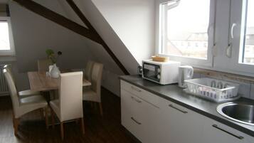 A compact kitchen with a dining area, featuring a microwave, toaster, and a small sink.