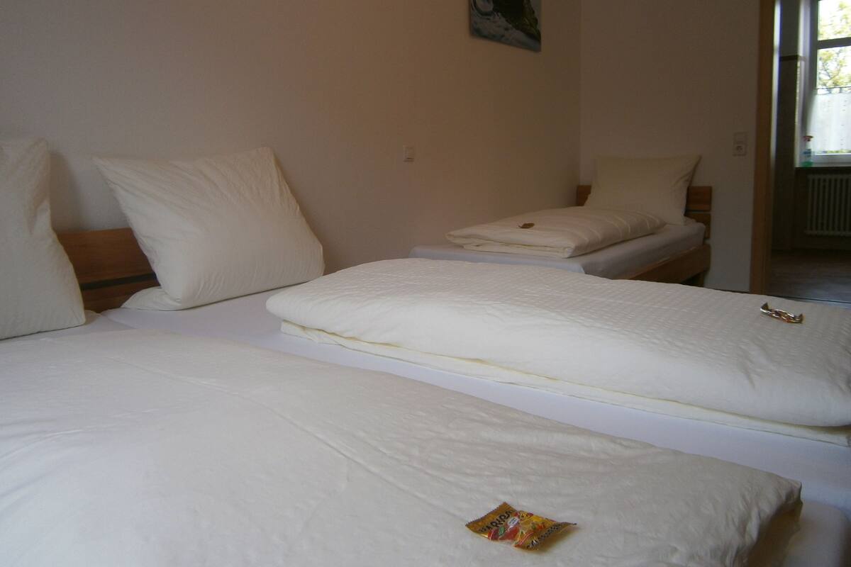 Een hotelkamer met twee bedden, witte beddengoed, een schilderij aan de muur en een raam.