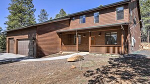 A two-story wooden house with a covered porch, a garage, and a well-maintained front yard with landscaping. - 3 Mi to Rainbow Lake: Home w/ Hot Tub & Deck (Pinetop-Lakeside)