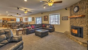 A spacious living room with a stone fireplace, leather sofas, and ceiling fans. - 3 Mi to Rainbow Lake: Home w/ Hot Tub & Deck (Pinetop-Lakeside)