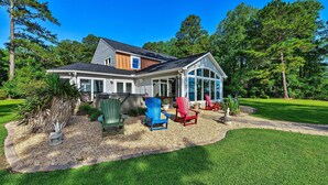 A house with a covered porch, outdoor seating, and a well-maintained lawn.