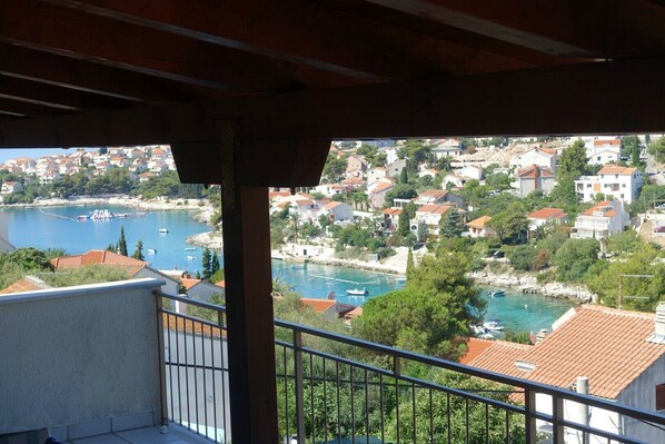 A balcony with a view of a coastal town, including a body of water and buildings.