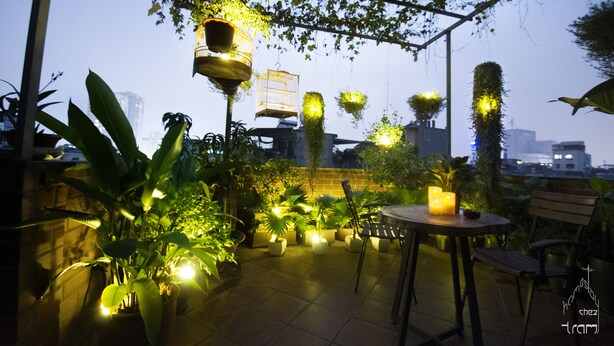 Ein möblierter Außenbereich mit Terrasse, Kübelpflanzen und hängenden Pflanzgefäßen.