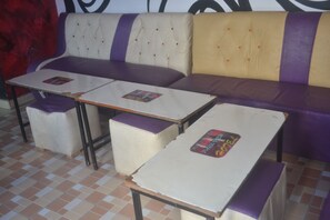 A seating area with two tables and cushioned benches, featuring a checkered floor pattern. - Maendeleo Parkview Hotel (Narok)