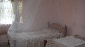 A bedroom with a single bed, a bedside table, and a window with a curtain. - Maendeleo Parkview Hotel (Narok)