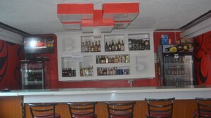 A bar area with a counter, multiple shelves of bottles, and bar stools. - Maendeleo Parkview Hotel (Narok)