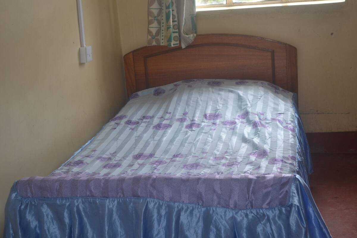 Uma cama de solteiro com colcha floral e saia azul.