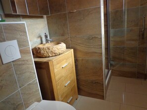 A bathroom with a stone sink, wooden cabinet, and tiled walls. - Bungalow 1 - Apartment and bungalow in Trassenheide (Zinnowitz)