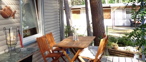 A wooden deck with a table and chairs, a lantern, and a fish decoration on the wall.