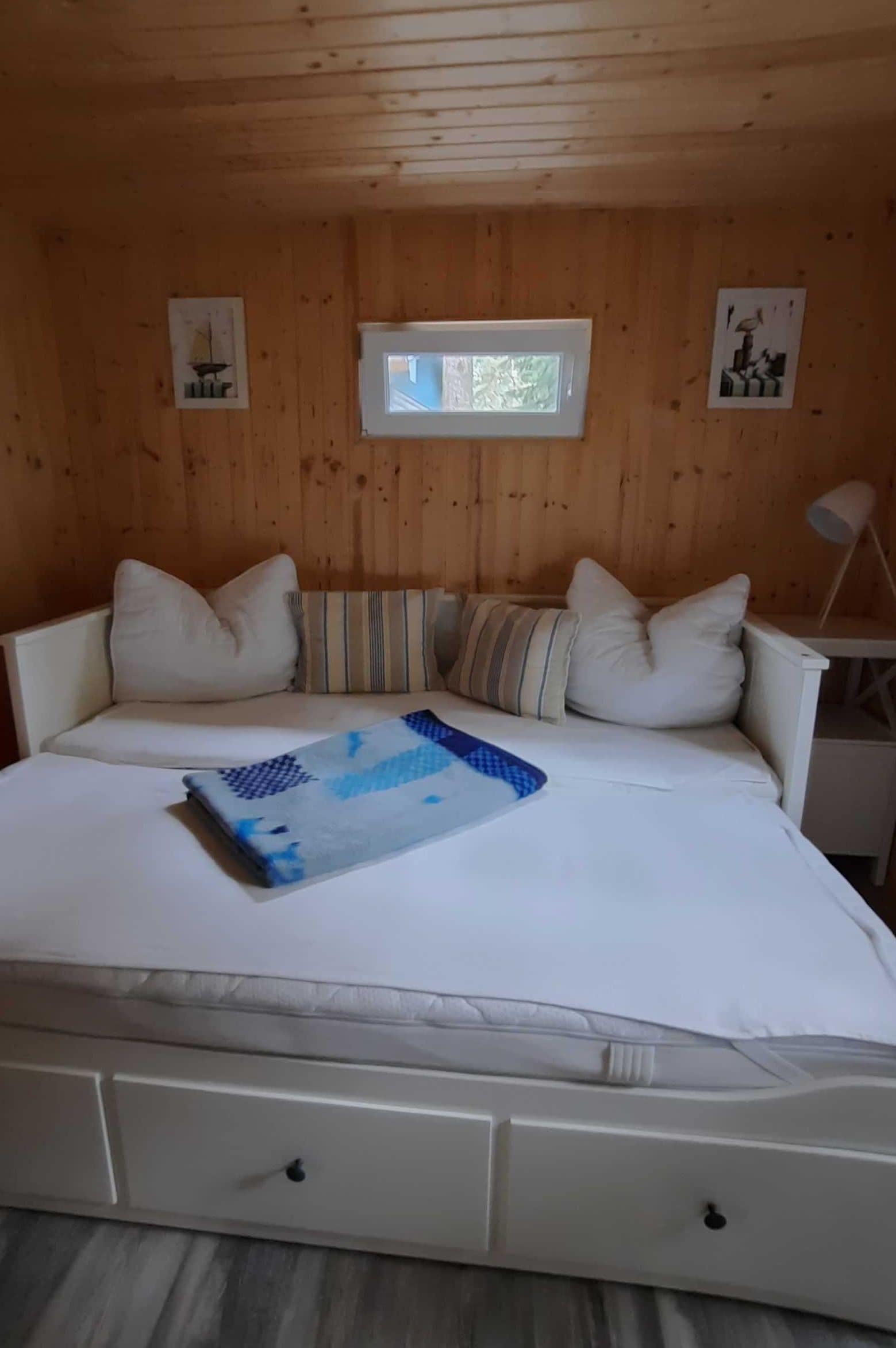 A bedroom with a bed, pillows, a window, and a lamp.